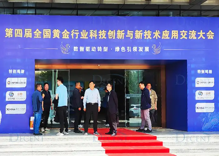 Qingdao Decent Group representatives attending the 4th National Gold Technology Exchange Conference, standing on a red carpet in front of a blue banner.