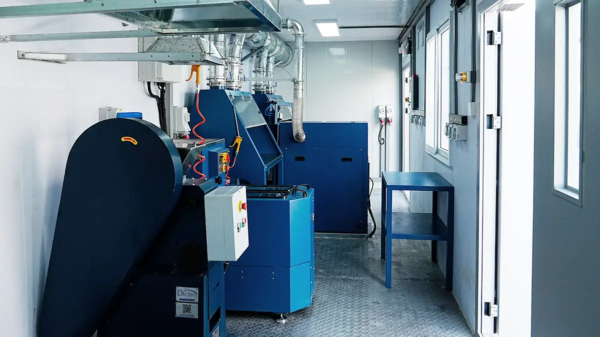 Interior of a DECENT Australia Mobile Container Laboratory Project 2025 sample preparation lab, showing blue industrial crushing and pulverizing equipment with extensive ventilation systems.
