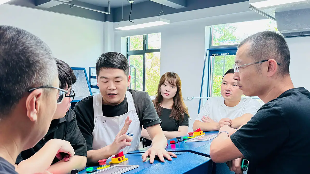 A group of professionals engaged in a discussion or training session in a laboratory or industrial setting, focusing on collaboration and system implementation.