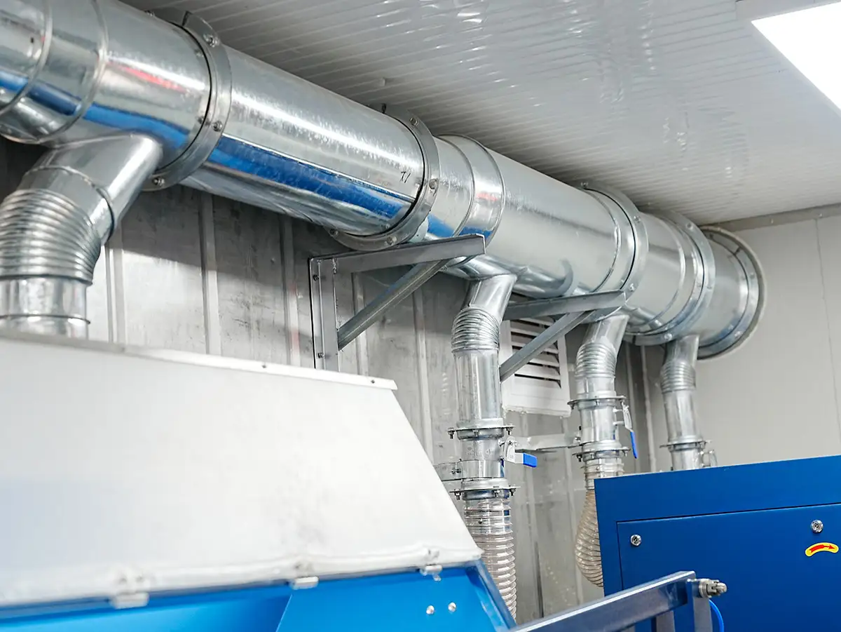 Galvanized steel ventilation ducts connecting blue sample preparation equipment inside a DECENT container laboratory.