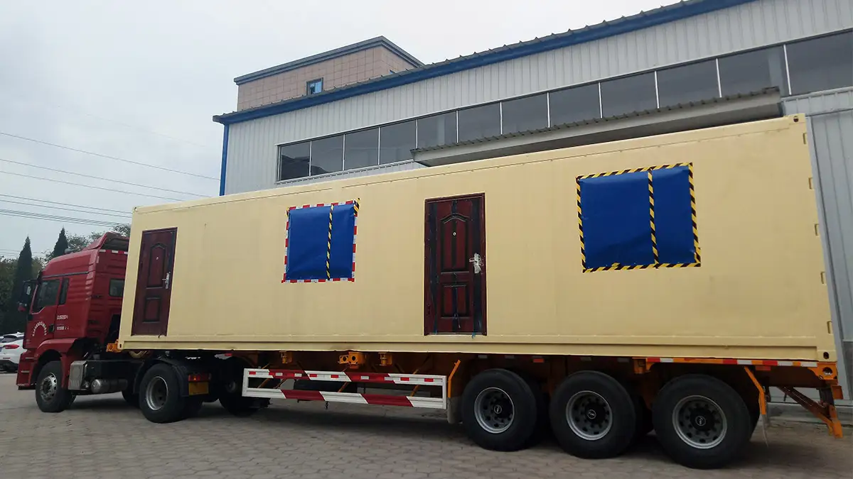 DECENT modular container unit on a truck, cream-colored with blue window covers, ready for transport, suitable for Chile Container Laboratories projects.