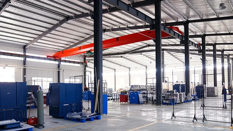A spacious and organized DECENT factory workshop with high ceilings, an overhead crane, and various blue industrial machines and equipment, indicating a manufacturing environment