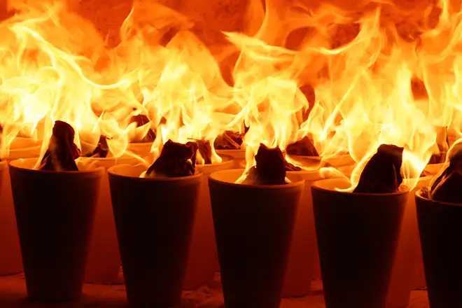Multiple crucibles engulfed in intense flames within a fire assay furnace, demonstrating the high-temperature fusion process.