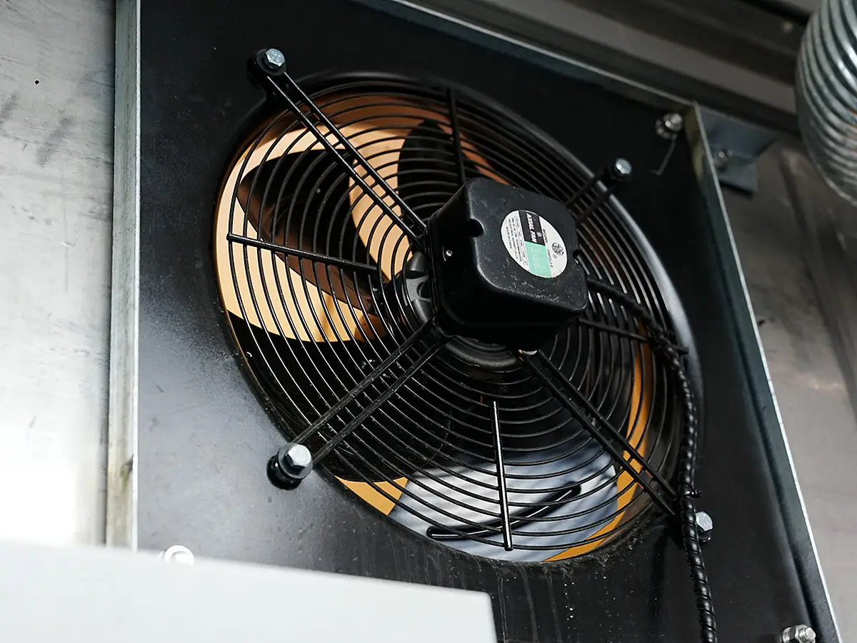 Close-up of a black industrial ventilation fan with orange blades, labeled 'Axial Fan', installed in a DECENT container laboratory.