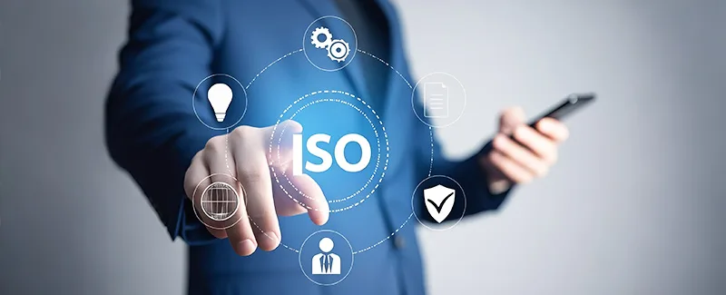 Business professional interacting with a holographic interface displaying 'ISO' at the center, surrounded by icons representing ideas, processes, documents, quality, and global reach, symbolizing DECENT's commitment to ISO standards