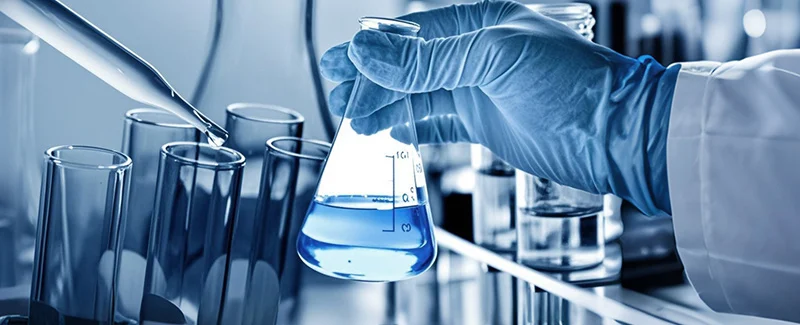 DECENT Laboratory Glassware: Hand in glove holding a flask with blue liquid, surrounded by test tubes