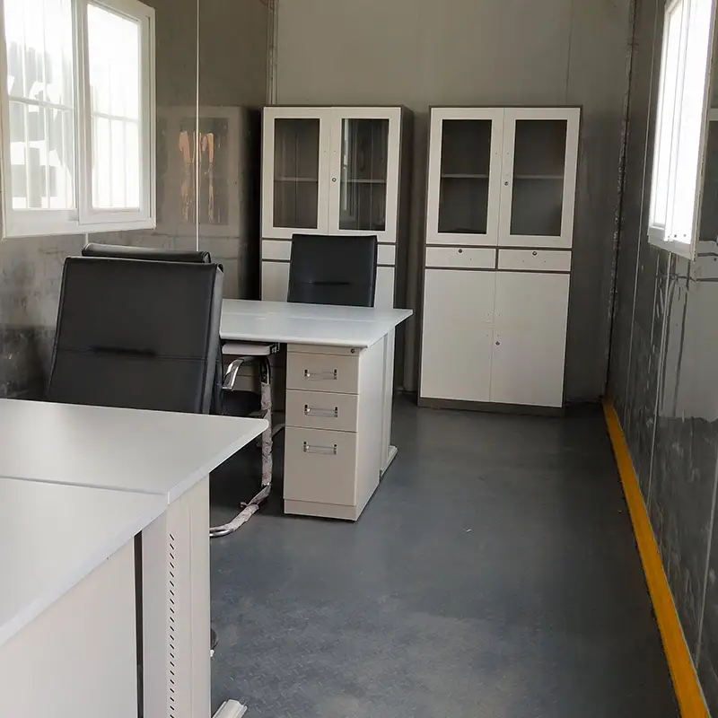 Interior of a DECENT modular container office with white desks, black chairs, and white storage cabinets, showing a complete portable workspace.