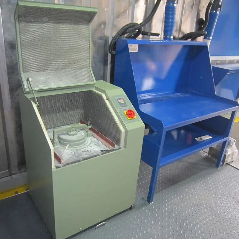 A pulverizer machine next to a blue metal workbench inside a lab container.