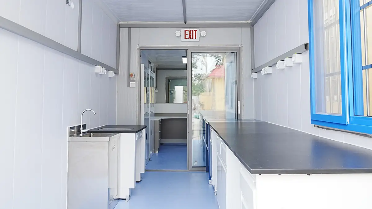 Interior of a DECENT Process-Control XRF Mobile Lab, showing the process control room with lab benches, a sink, and a sliding glass door leading to another section.