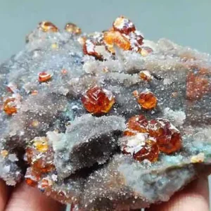 A stunning cluster of transparent, honey-orange sphalerite crystals, the primary zinc sulfide mineral, on a gray, sparkling matrix.