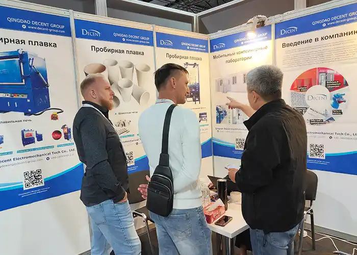 Qingdao Decent Group booth at Mining and Metals Central Asia 2025, featuring fire assay equipment and mobile container laboratories, with attendees discussing mineral laboratory solution.