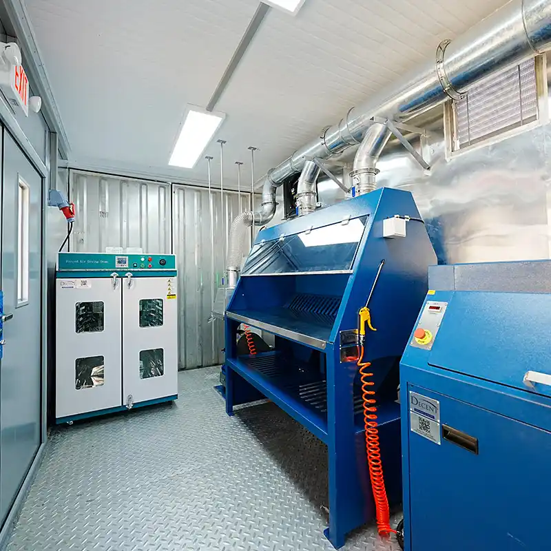 Interior of a DECENT containerized laboratory in Djibouti, showing a sample preparation area with an electric oven, blue workbench, and pulverizer mill.