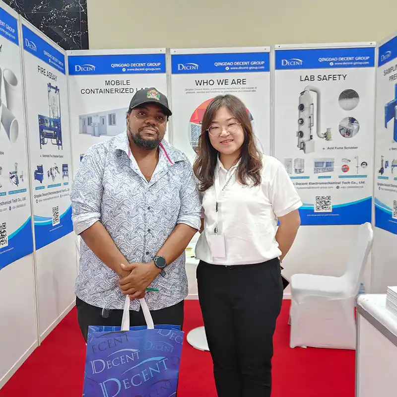 Qingdao Decent Group representative and a customer smiling at the DECENT booth at Minexpo Tanzania 2025, with the customer holding a DECENT branded bag, showcasing successful client interaction.